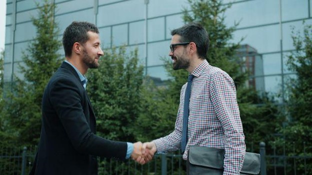 two people smiling and shaking hands